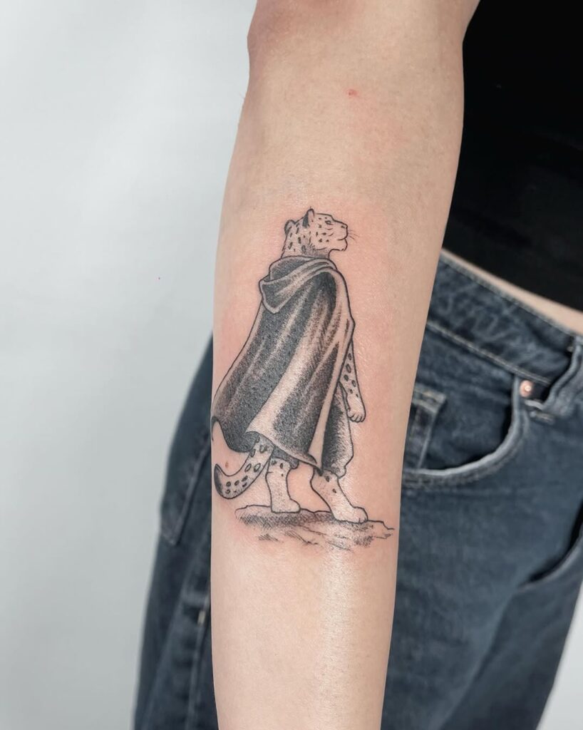 Tatuagem autoral de onça com moletom e crocs no antebraço — estúdio Flag Haus, Vila Mariana, São Paulo