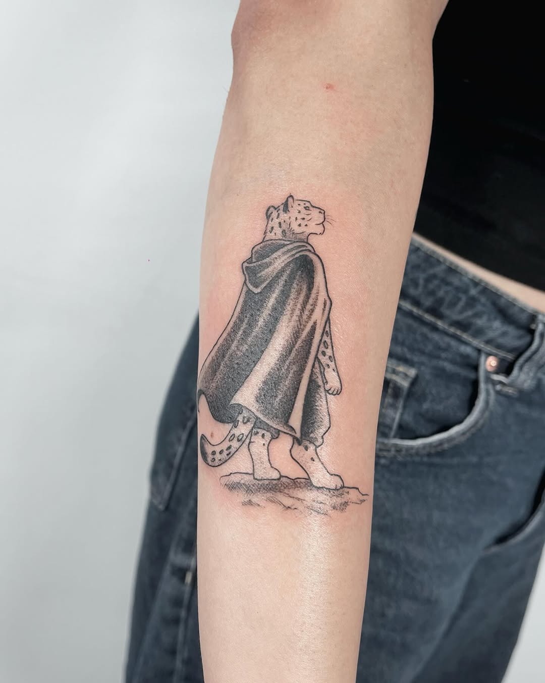 Tatuagem autoral de onça com moletom e crocs no antebraço — estúdio Flag Haus, Vila Mariana, São Paulo