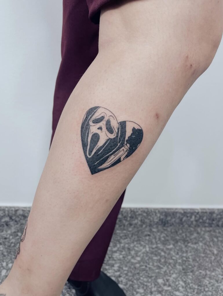 Tatuagem blackwork do Ghostface do filme Scream em moldura de coração na perna, feita por Julio Bandeiras na Flag Haus