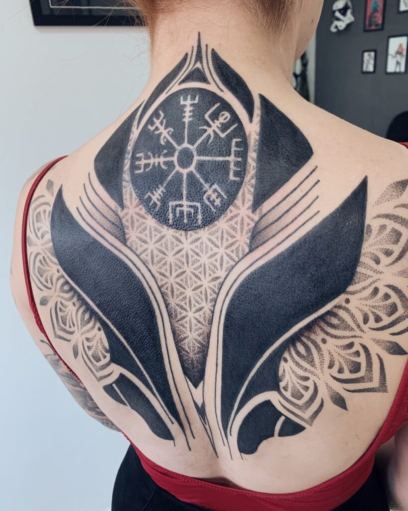 Tatuagem geométrica de larga escala nas costas com blackwork, vegvisir, flor da vida e mandalas, realizada na Flag Haus, Vila Mariana, São Paulo