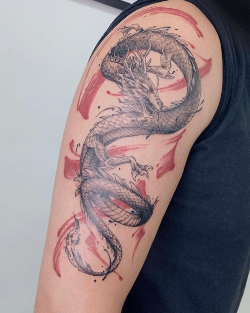 Tatuagem de dragão oriental em gray wash com pinceladas em vermelho no braço, realizada na Flag Haus, Vila Mariana, São Paulo
